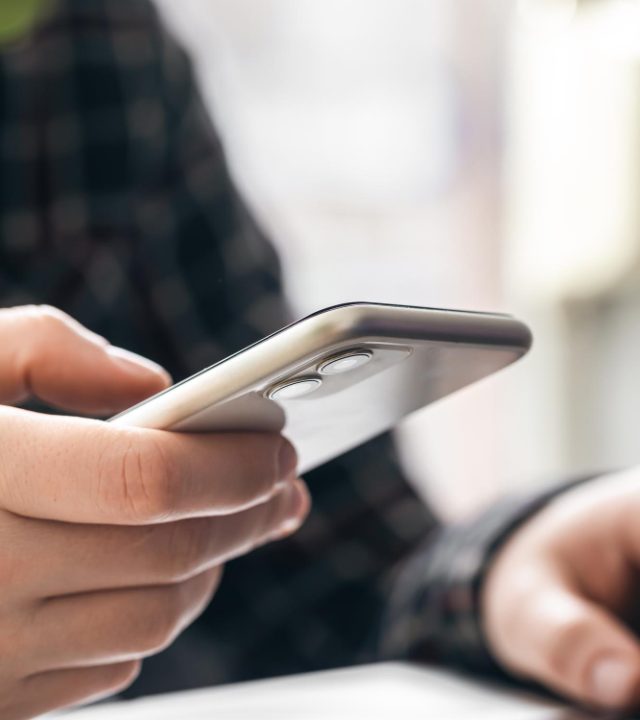 hombre-sostiene-telefono-inteligente-trabaja-computadora-portatil